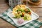 Fresh Greek salad on white plate with pita tomato feta cheese cucumber and onion on wooden table