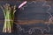 Fresh green asparagus bunch decorated with pink thread on the black wooden background. Top view copy space
