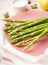 Fresh green asparagus in a plate on a beige background, close-up