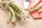 Fresh green asparagus on a table and in a white plate, tied with a rope, with a knife on a red napkin