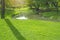 Fresh green carpet grass yard, smooth lawn in a beautiful garden and good care landscaping, beside a curve long lake and trees