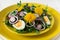 Fresh green dandelion salad on yellow plate