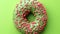 Fresh green glazed ring donut covered by pink pastry topping rotating. Shot with RED camera in 4K