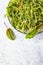 Fresh green mixed salad with microgreens with water drops on a plate, blue concrete background. Healthy food. Top view