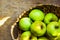 Fresh green organic apples in wicker basket on rustic wooden table sunlight. Local farming produce healthy plant based diet