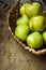 Fresh green organic ecological apples in wicker basket on rustic wooden table, top view, still life