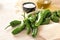 Fresh green pimientos or padron peppers, olive oil and coarse sea salt on a napkin and a light wooden table, ingredients for a