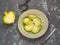 Fresh green radish sliced into slices lies on a ceramic olive plate, with a fork and a peeler lie on a gray spotted