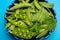 Fresh green ripe sugar snaps, sweet peas in bowl copy space close up on blue background