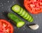 Fresh green sliced cucumber and tomato on a black stone background.