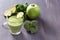 Fresh green smoothies with parsley, broccoli, apple, lime and mint in a glass on a black wooden table with low back light