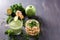 Fresh green smoothies with parsley, ginger, apple, lime, and mint in a glass on a black wooden table next to Puffed wheat cake