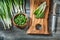 Fresh green spring scallions wooden cutting board kitchen knife vintage wood background