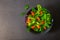 Fresh green vegetable salad. Top view from above of cherry tomato, basil, spinach and lettuce, red cabbage in black bowl.