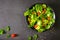 Fresh green vegetable salad. View from above of cherry tomato, onion, spinach and lettuce in black bowl. Healthy concept, home mad