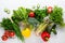 Fresh green vegetables and summer produce on white surface