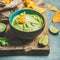 Fresh guacamole sauce in blue bowl and chips, square crop