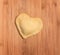 Fresh,handmade single raviolo in the shape of heart,covered with flour and placed on the wooden table.