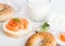 Fresh healthy bagel sandwich with salmon, ricotta and glass of milk on light kitchen table background. Healthy diet food.