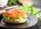 Fresh healthy bagel sandwich with salmon, ricotta and lettuce on black plate on black kitchen table background. Healthy diet food