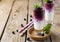 Fresh healthy blueberry smoothies in a glass with berries and mint leaves on a wooden stand.