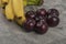 Fresh healthy plums with banana cluster on stone background