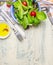 Fresh healthy salad with lettuce , cherry tomatoes and radish on light rustic background with cutlery and olive oil, top view, pla