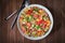 Fresh healthy salad with quinoa, colorful tomatoes, sweet pepper, cucumber and parsley on wooden background top view.