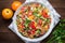 Fresh healthy salad with quinoa, colorful tomatoes, sweet pepper, cucumber and parsley on wooden background top view.