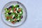 Fresh healthy summer salad with figs, white cheese, arugula and black olives on gray ceramic plate on gray background. Top down