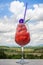 Fresh healthy watermelon smoothie in the glass against the background of sky, clouds, and mountains