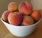 Fresh homegrown peaches heaped in a white bowl