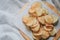 Fresh homemade deep fried crispy potato chips in white box on a wooden tray, top view. Salty crisps scattered on a table