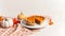 Fresh homemade pumpkin pie on a white plate with pumpkins and autumn leaves.