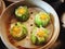Fresh and hot Chinese green dumplings in wooden basket ready to eat