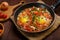 fresh hot shakshuka in a frying pan sprinkled with green onions on a set Shabbat table.