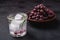 Fresh ice cold carbonated water in glass with rosemary leaf near to wooden bowl with grape berries, dark stone background