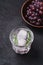 Fresh ice cold carbonated water in glass with rosemary leaf near to wooden bowl with grape berries, dark stone background