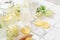 Fresh iced mocktail or lemonade with lemons and elderflowers in glasses on white tile table with hard light and shadows