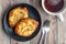 Fresh individual apple tarts on a black plate, forks, cup of hot tea, wood background