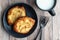 Fresh individual apple tarts on a black plate, forks, mug of cold milk, wood background