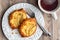 Fresh individual apple tarts on a white plate, forks, cup of hot tea, wood background