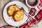 Fresh individual apple tarts on a white plate with forks, cup of milk, red, green, and white cloth napkin, wood background