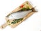 Fresh Indo-Pacific tarpon fish decorated with herbs and vegetables on a wooden pad,Selective focus.White background