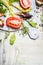 Fresh ingredients for tasty salad on round white cutting board and wooden background, top view