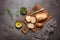 Fresh Italian ciabatta bread in slices on a wooden cutting board with olive oil, olives and rosemary, dark rustic background. Top
