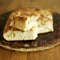 Fresh Italian focaccia bread with broken piece on top. Conceptual image