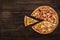 Fresh italian pizza and a pie spatula with one slice on the wooden background. Top view and copy space for text