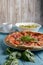 Fresh italian pizza with salami and black olives and other food on the background. Blue colored wooden table