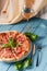 Fresh italian pizza with salami and black olives and other food on the background. Blue colored wooden table